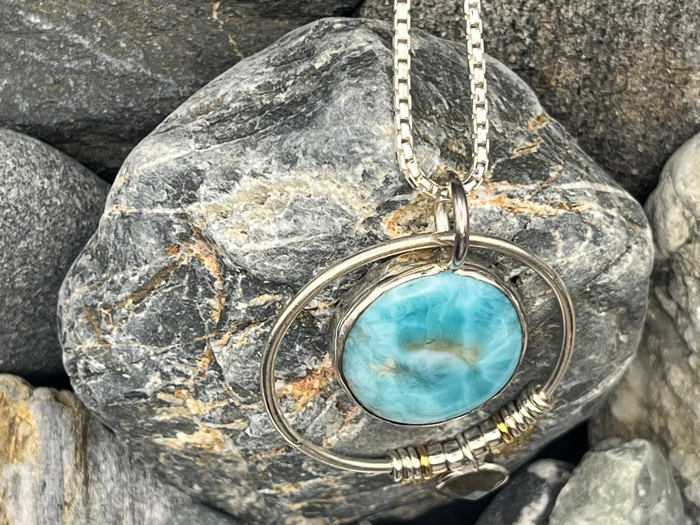 Larimar stone pendant on a chain resting on a rock