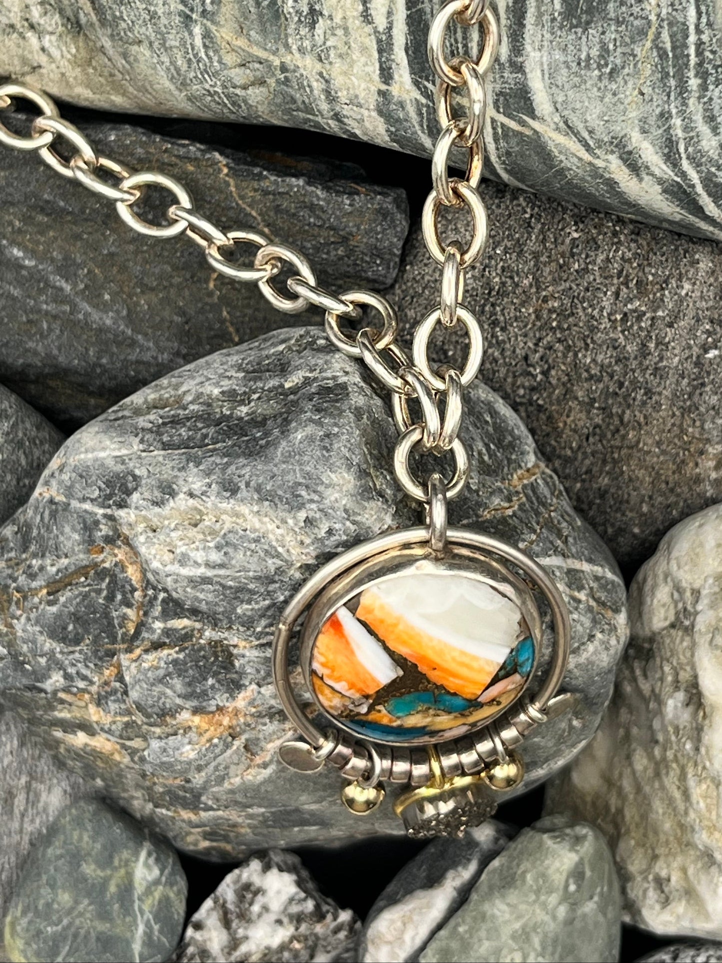 Necklace with a colorful stone pendant on rocks