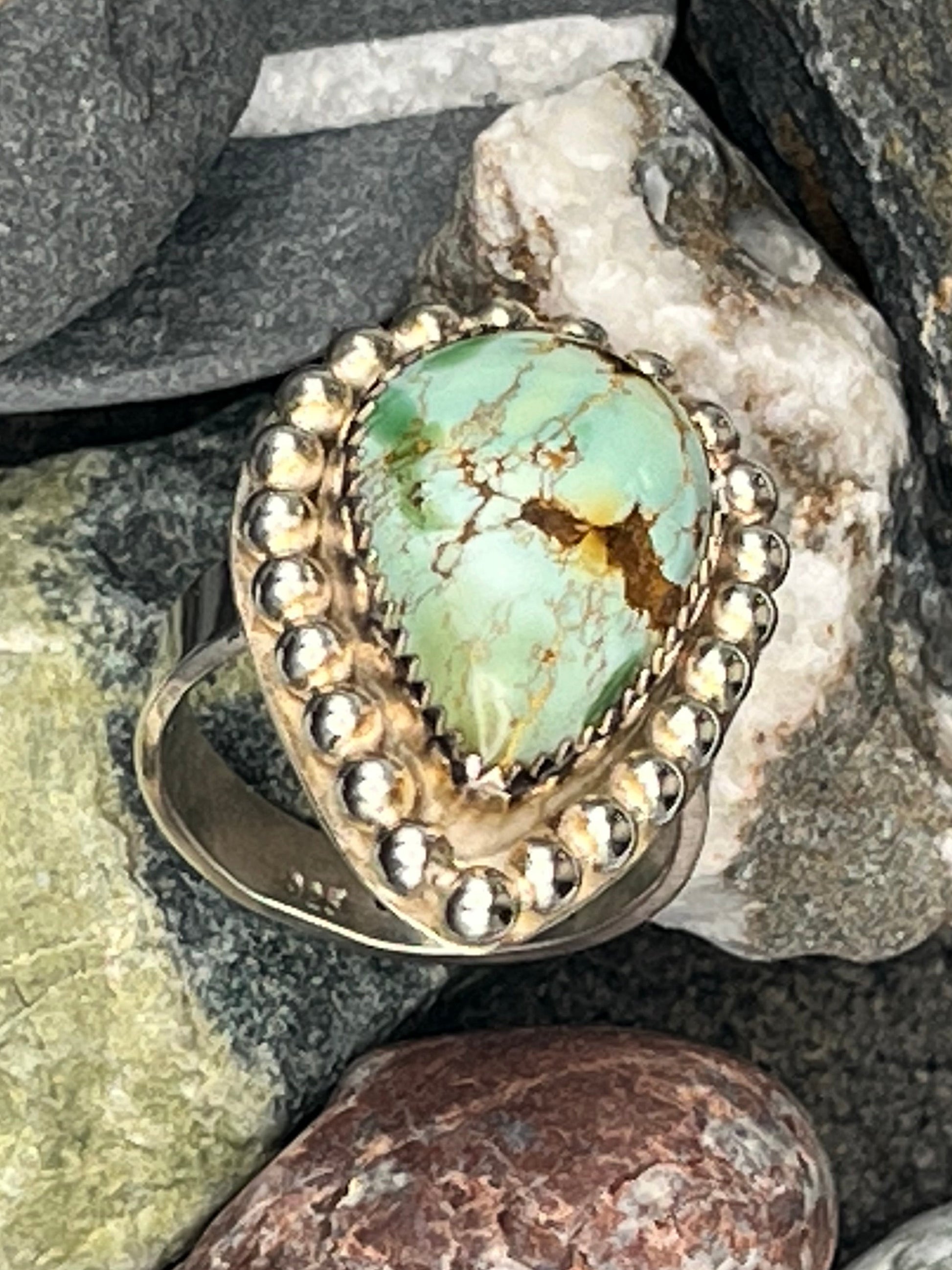 Silver ring with turquoise stone on a bed of rocks