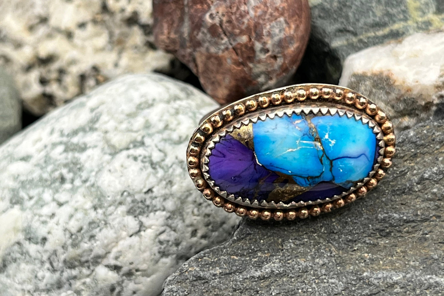 Ring with blue stone and gold setting on a rock