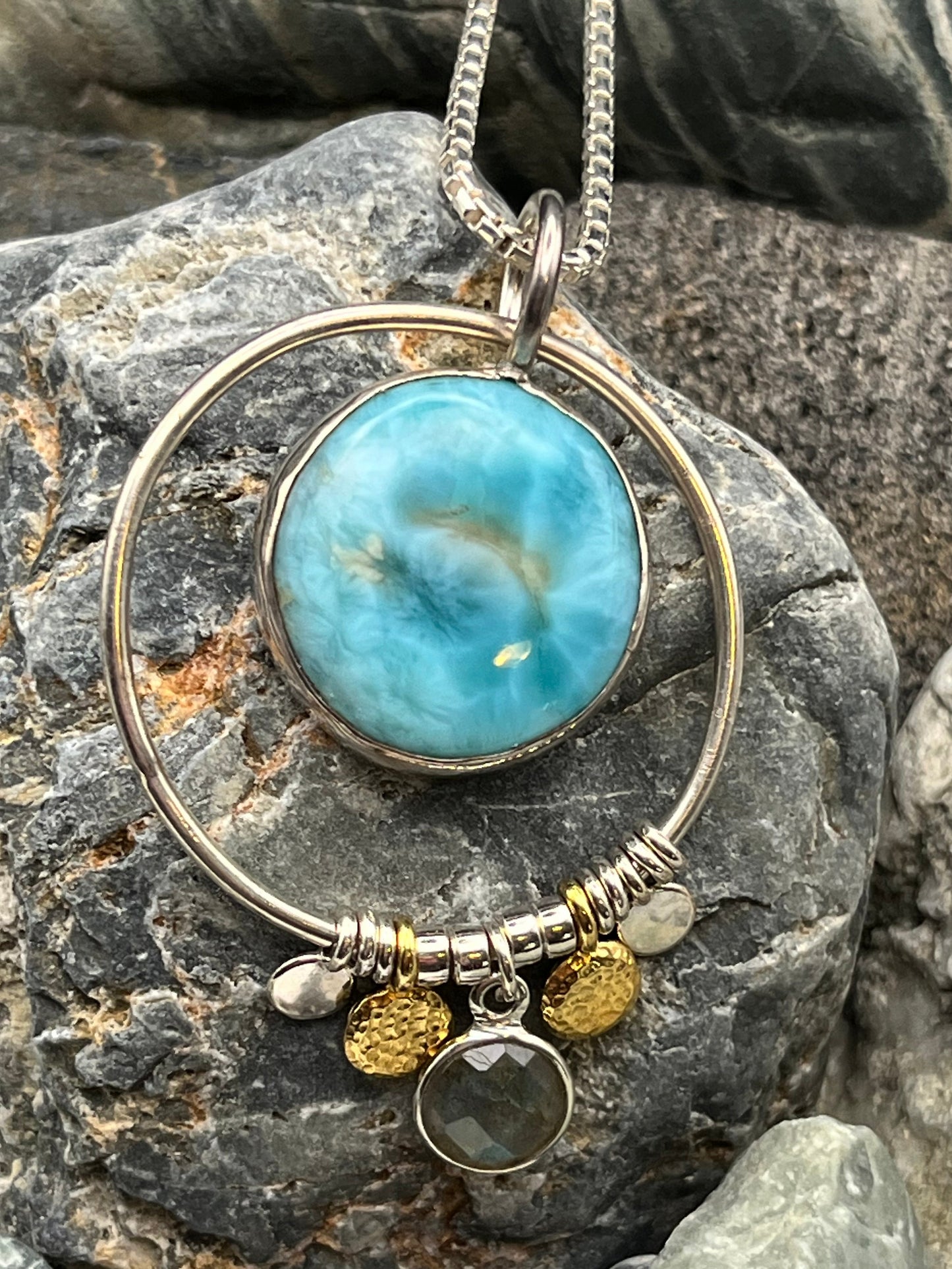 Necklace with a large blue Larimar stone pendant on a rocky surface