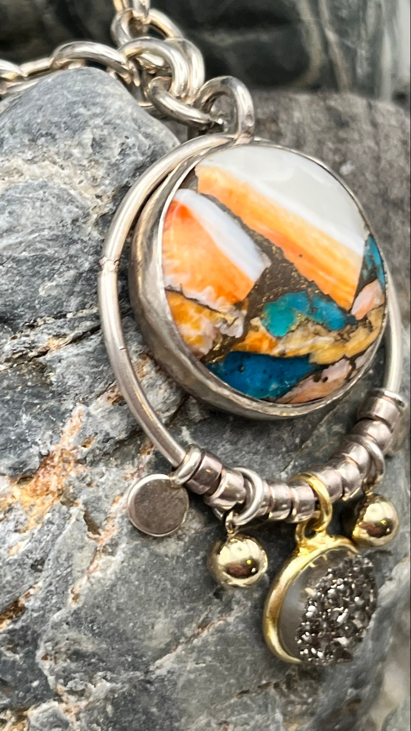 Silver necklace with a round pendant on a textured stone surface