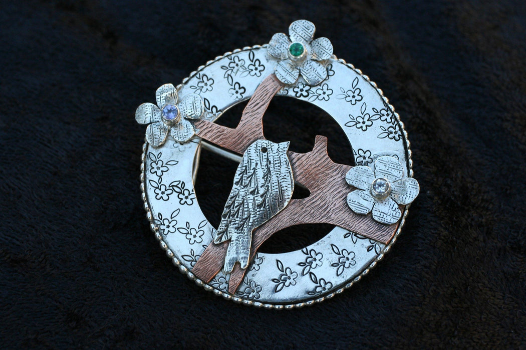 Bird pendant as brooch pin with tanzanite, emerald, and aqua marine.